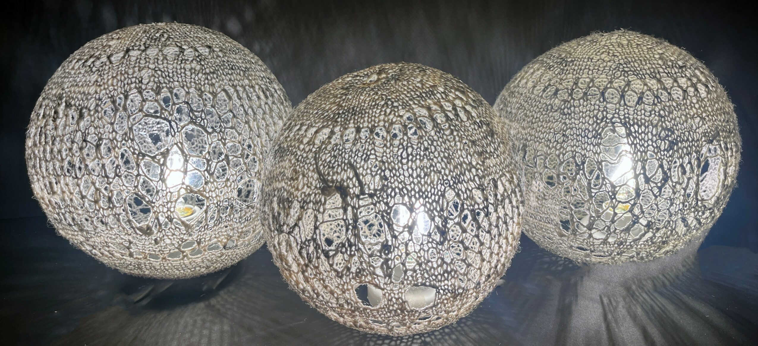 Three spherical decorative lamps with intricate patterns, placed on a reflective surface, against a dark background.