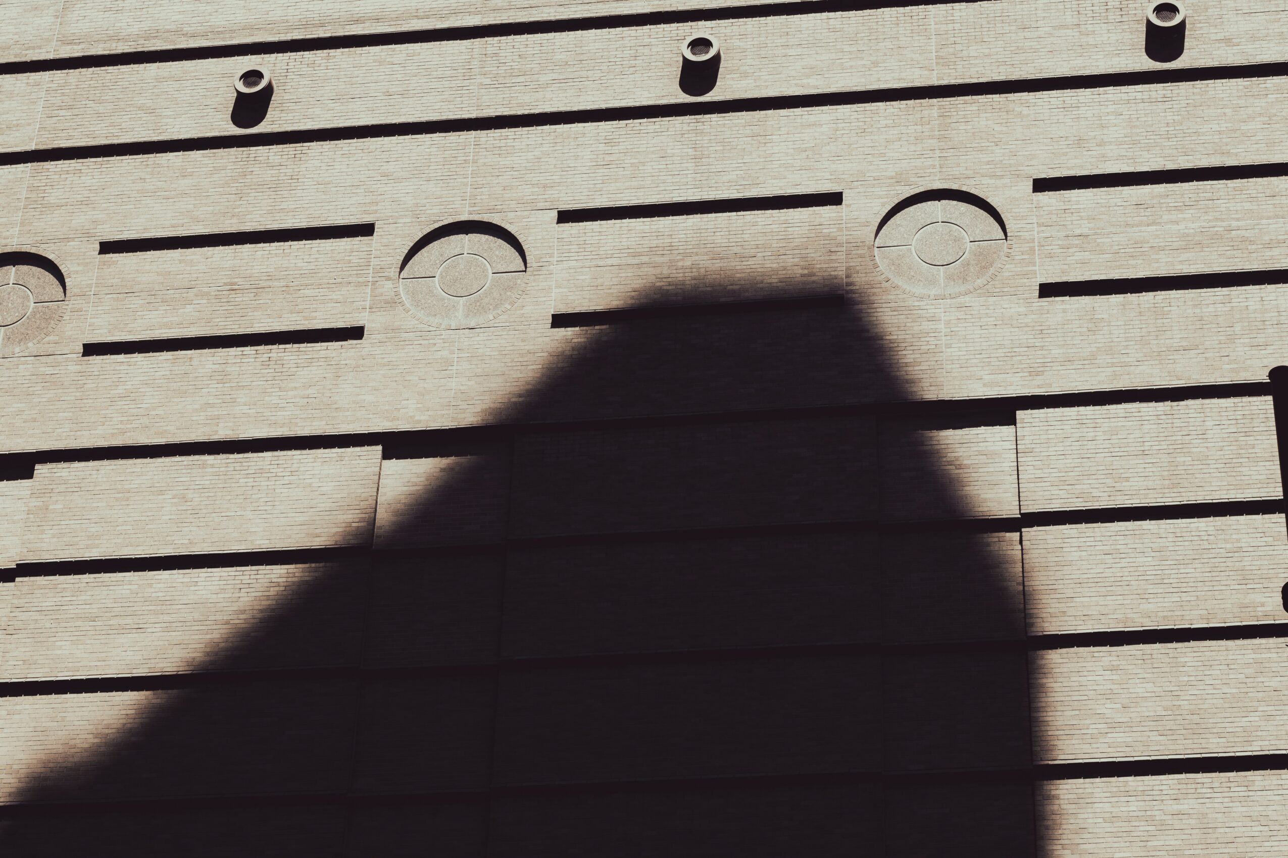 Shadow of a person on a wooden surface with horizontal lines and circular indentations.
