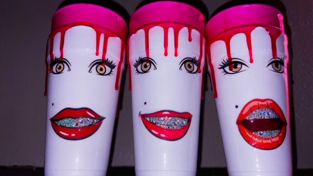 Three white bottles with pink caps, decorated with stylized faces, red lips, and dripping paint design.