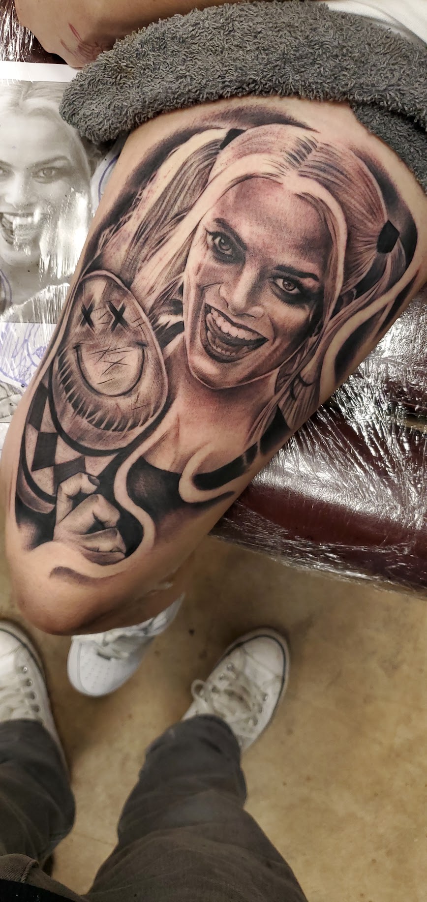 Tattoo of a smiling woman with long hair on person's upper arm, with other designs around it.