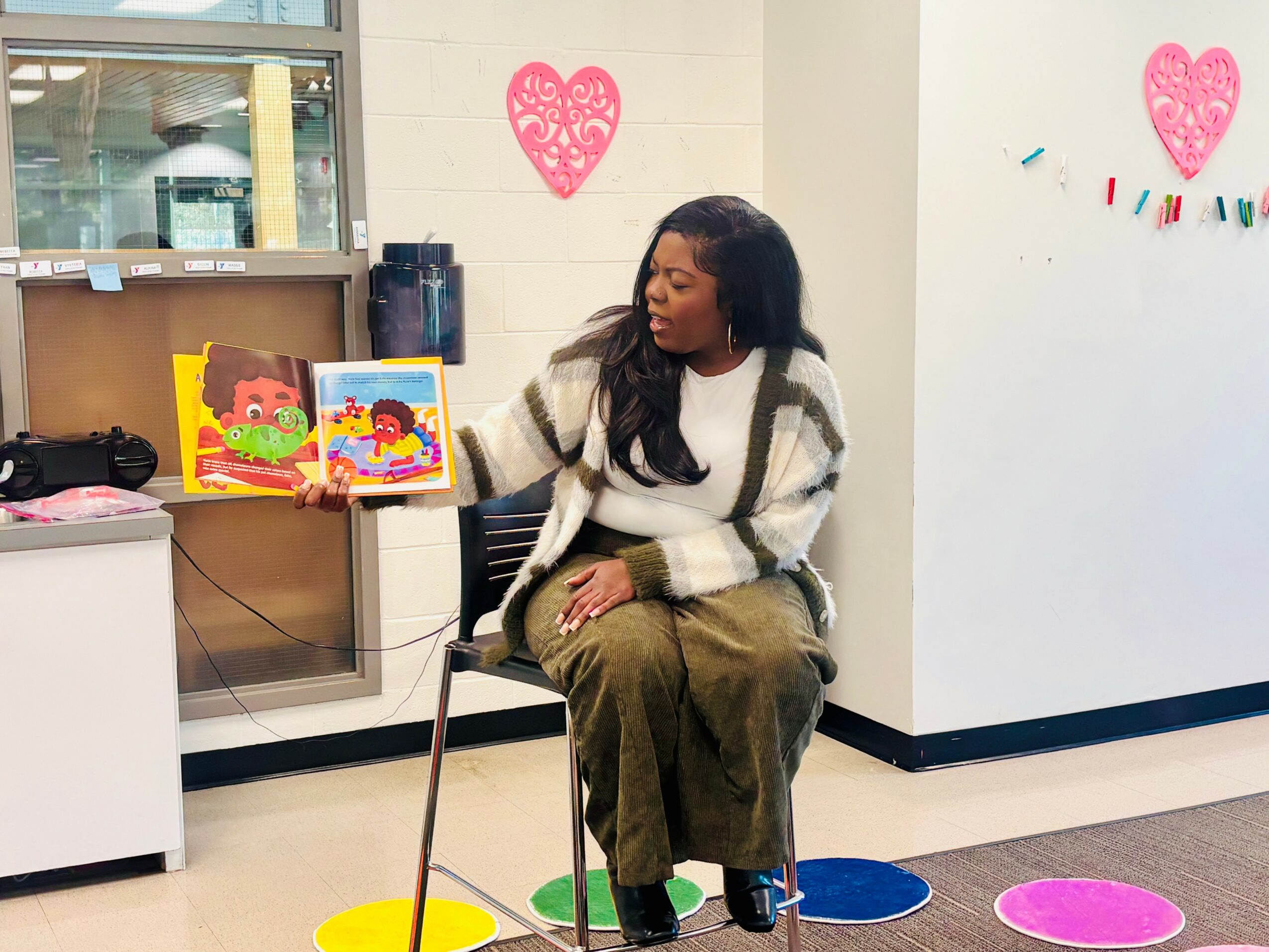 Woman sitting on a chair in a room with colorful decorations and books, looking to the side.