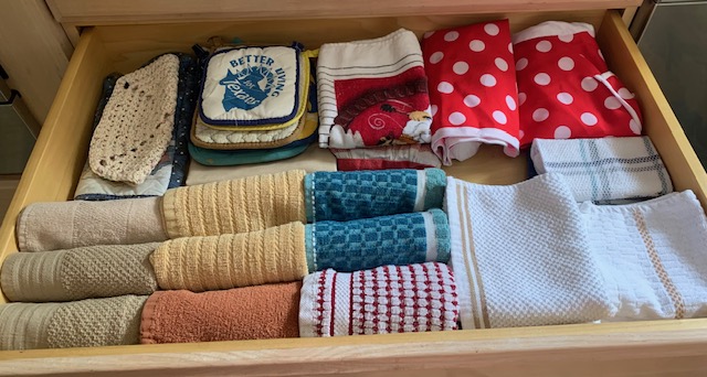 Drawer containing neatly folded socks and cloths in various colors and patterns, including polka dots and stripes.