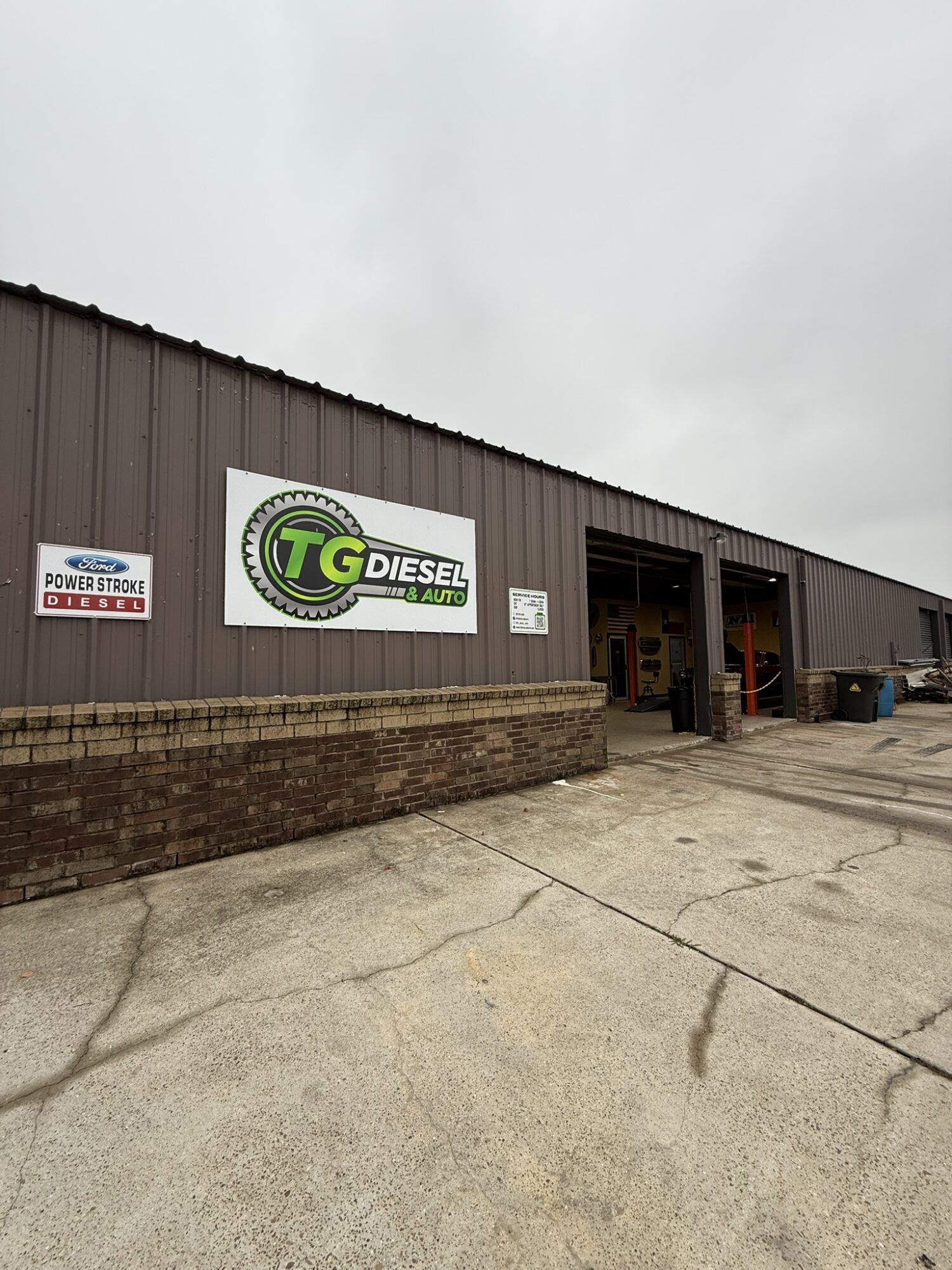 Exterior view of a building with a sign reading 'TG Diesel' and an open entrance, under a cloudy sky.