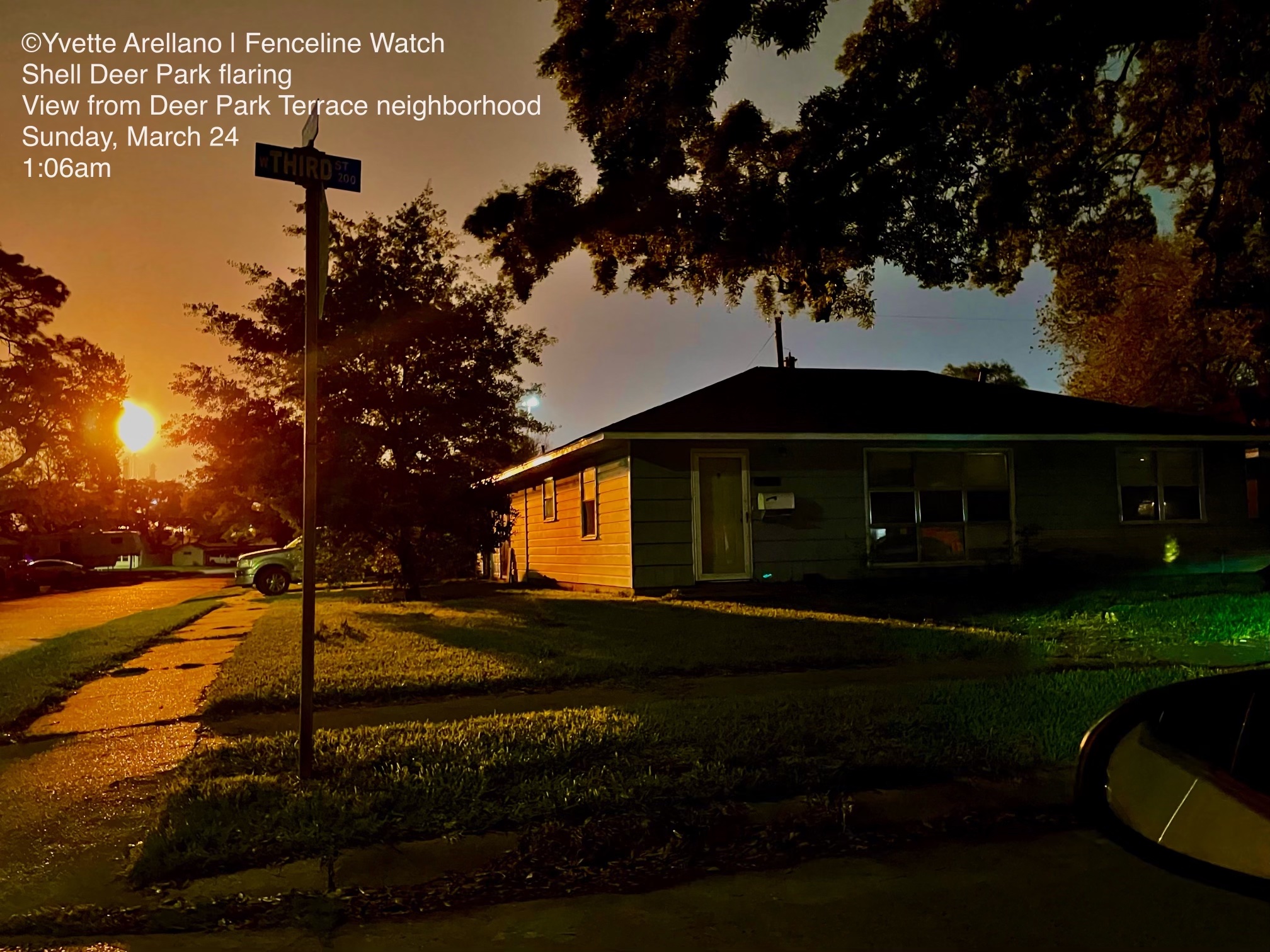 Sunset scene with a house, trees, and a streetlamp, with the sun near the horizon and a car's side mirror visible.