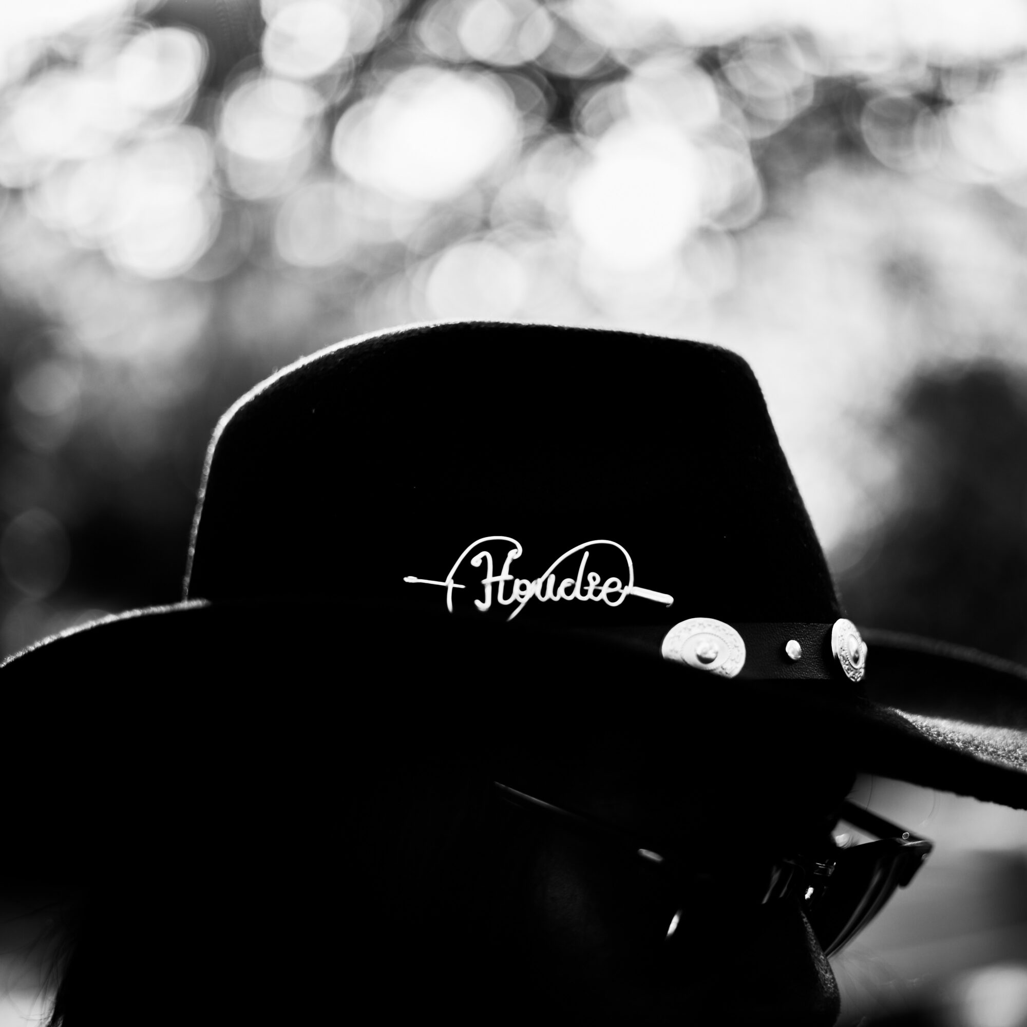Black hat with decorative pins and sunglasses, background with blurred light spots