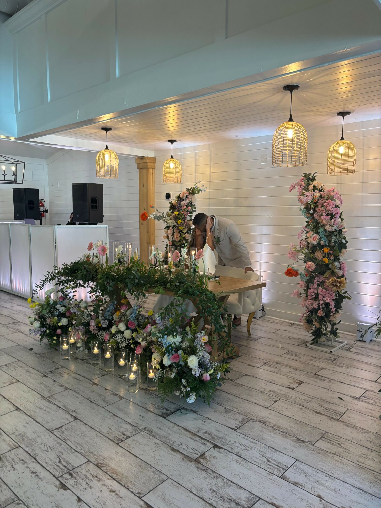 Person arranging flowers in a decorated room with hanging lamps and floral displays on the floor.