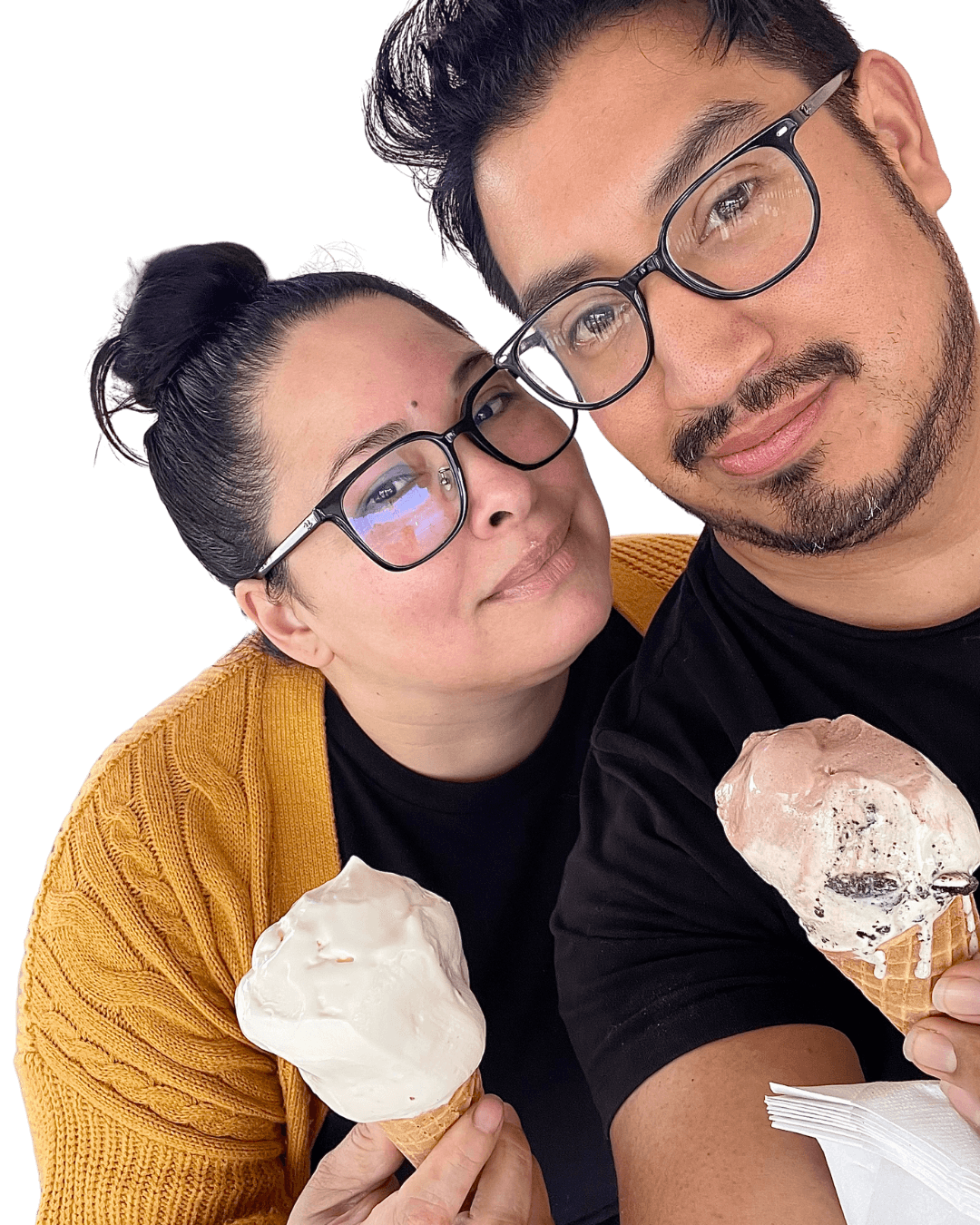 Two people wearing glasses holding ice cream cones, smiling, with a dark background.