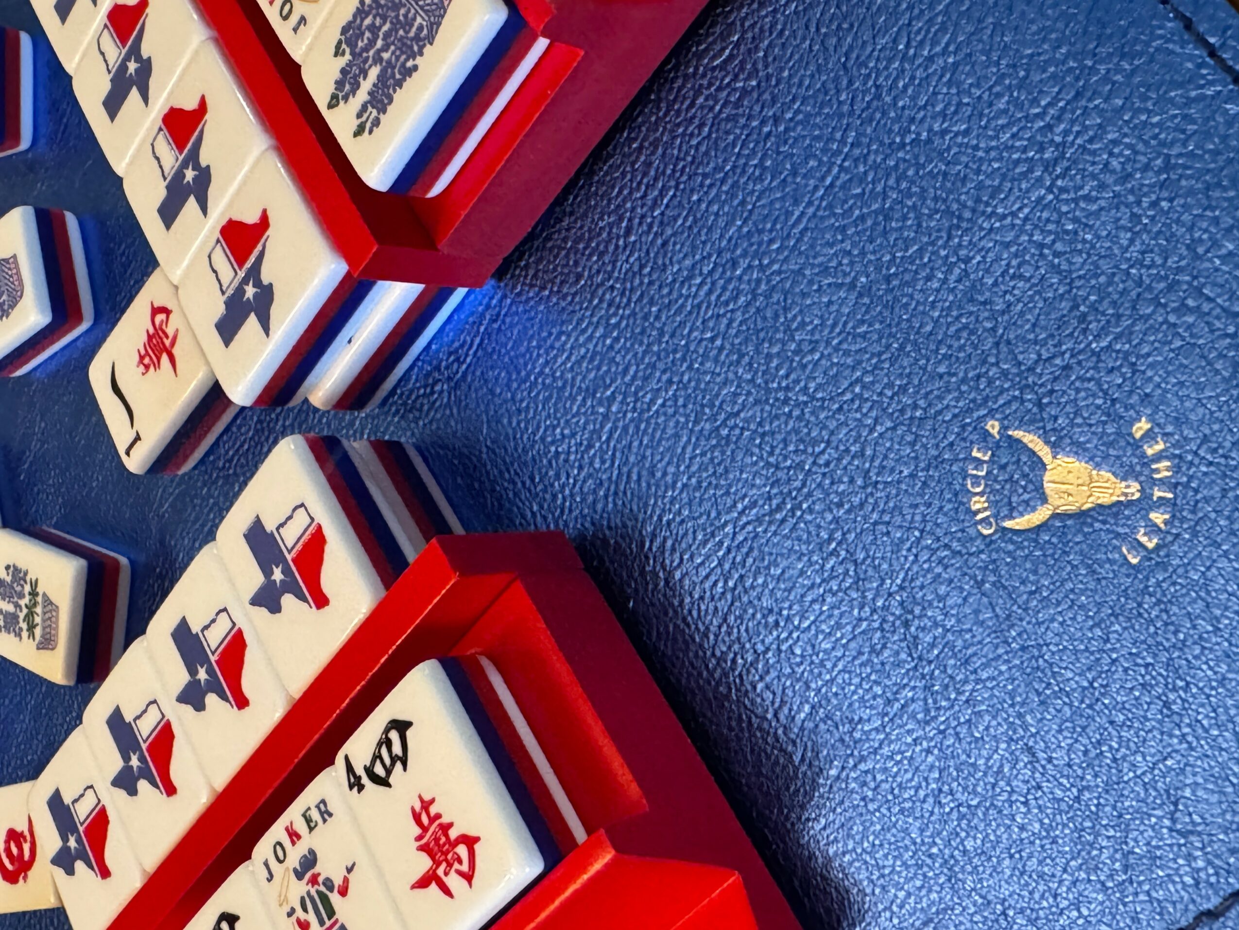 Playing cards in red boxes on a blue textured surface with a small logo of a figure holding a torch.