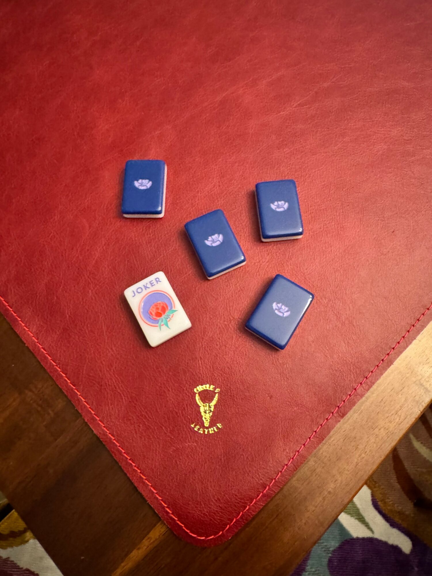Five small rectangular objects, four blue and one white, are arranged on a red surface with a gold emblem.