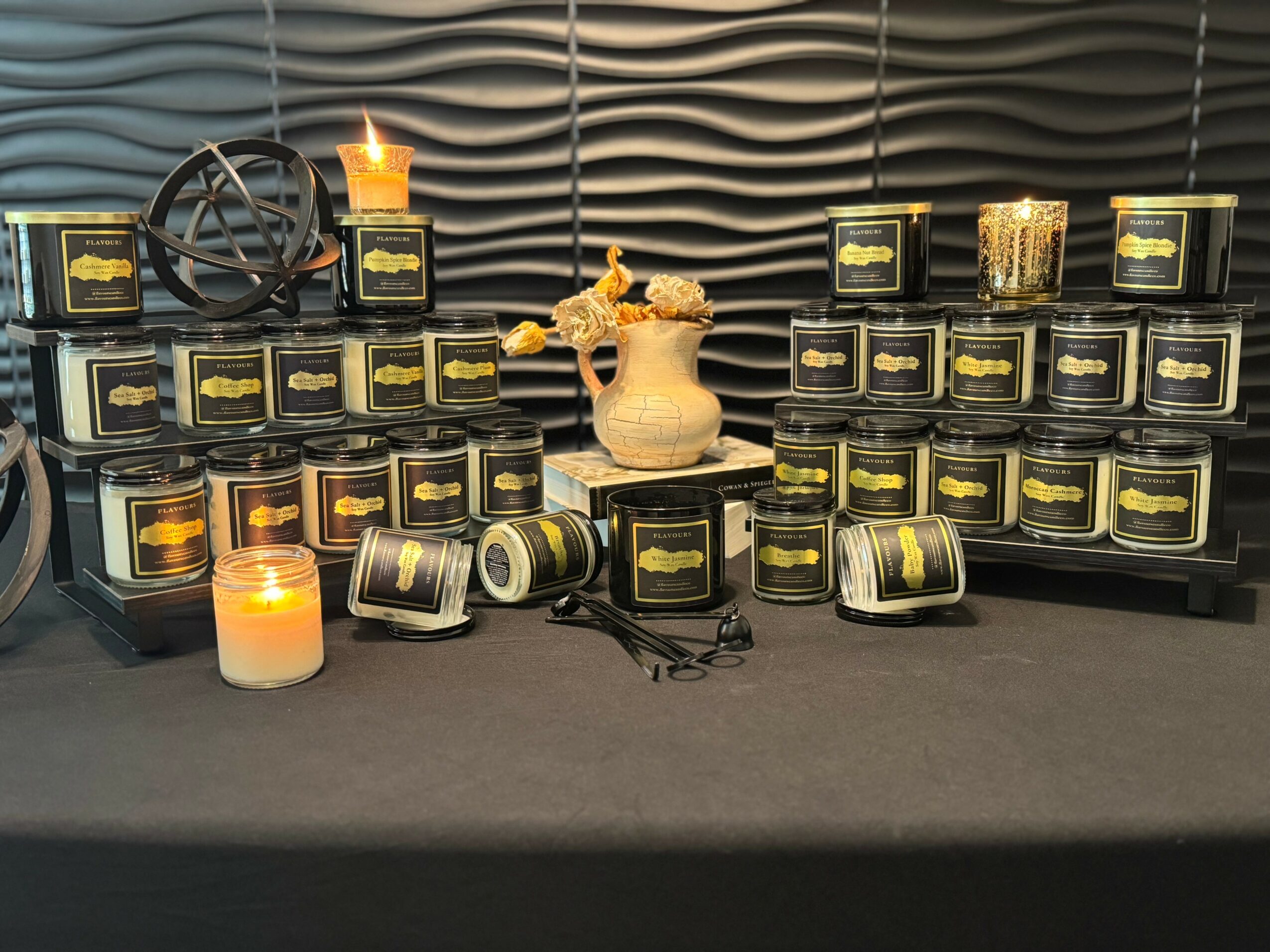 Display of candles, a candle holder, and a decorative object on a table with a textured background.