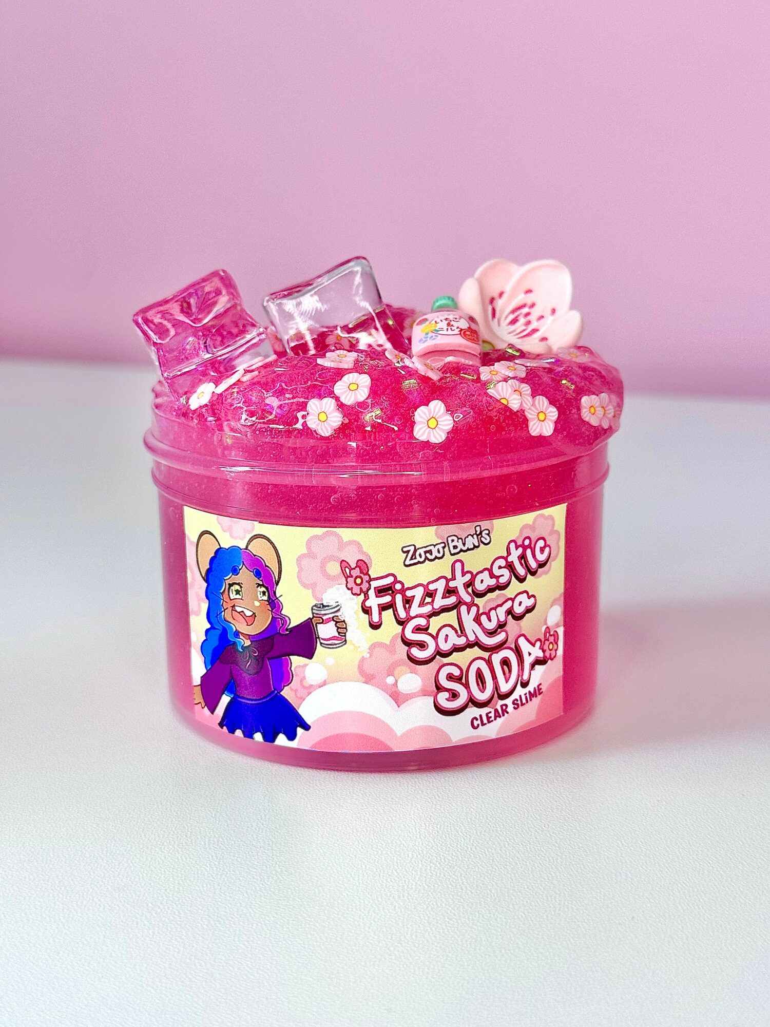 Pink container with a character and text, filled with pink slime, small bottles, and a heart-shaped object.