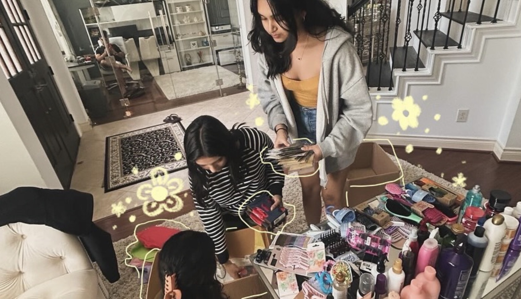 Two women and a child in a cluttered room with various bottles and items on a table, staircase in background.