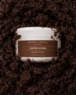 Container of coffee scrub surrounded by coffee grounds, label reads 'Exfoliants by Malka, Coffee Scrub, Gentle Exfoliant'.