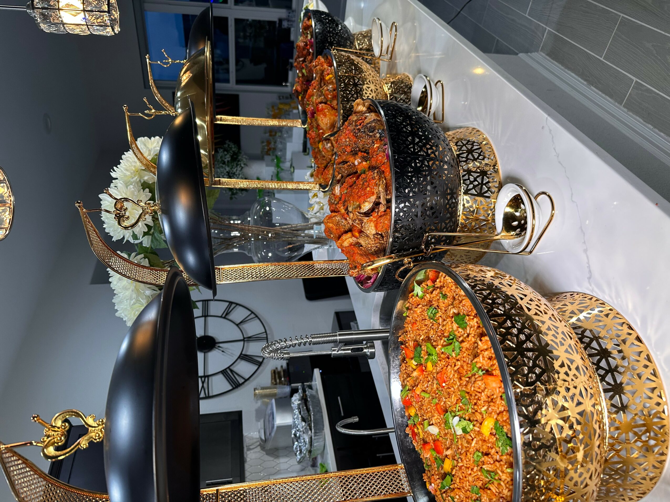 Table with various dishes, decorative items, and a clock in the background, viewed from the side.