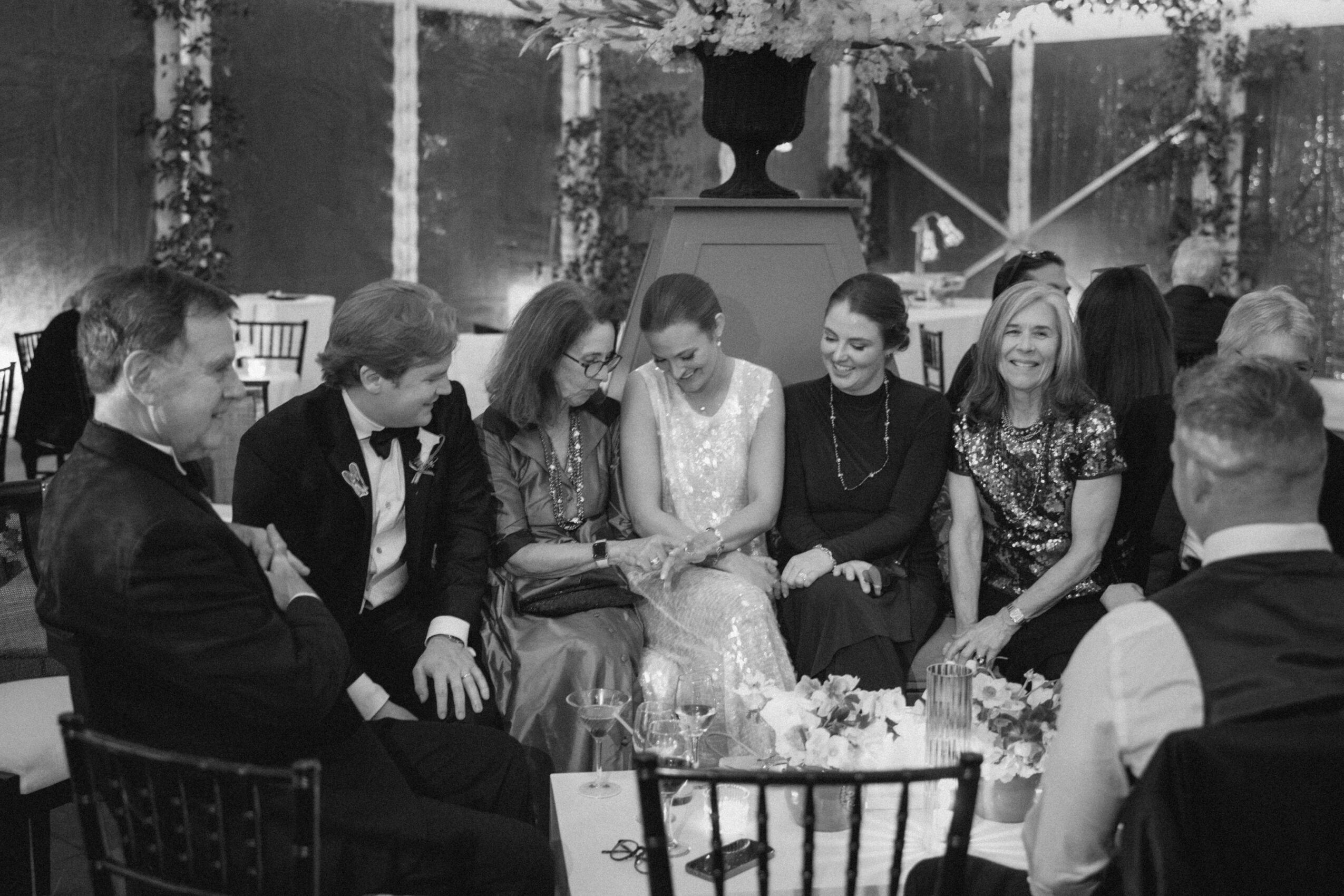 Group of people sitting together at a table, engaged in conversation, in a decorated indoor setting.