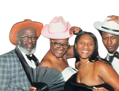 Four people dressed in formal attire, smiling, with two wearing hats, posing together against a white background.