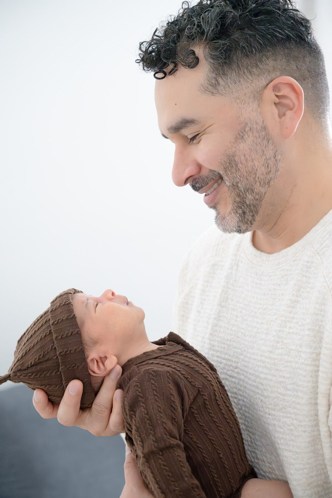 Man holding a baby, both smiling, against a plain white background.