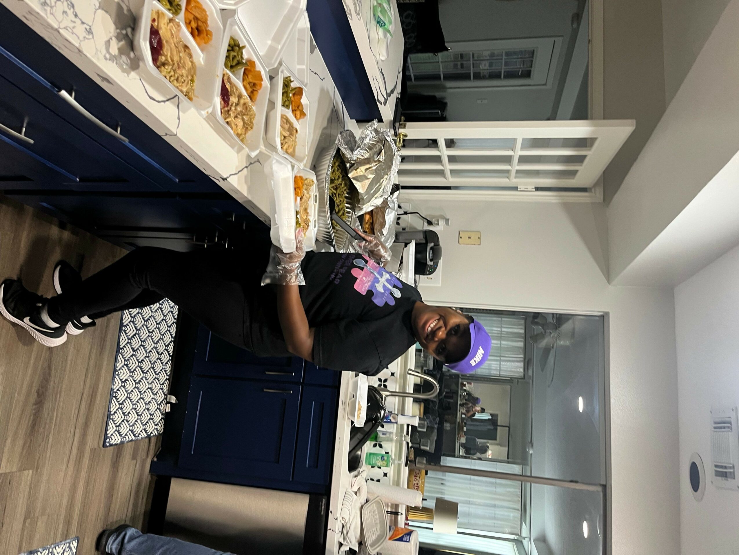 Person wearing a purple helmet preparing food in a kitchen with blue cabinets and a white countertop.