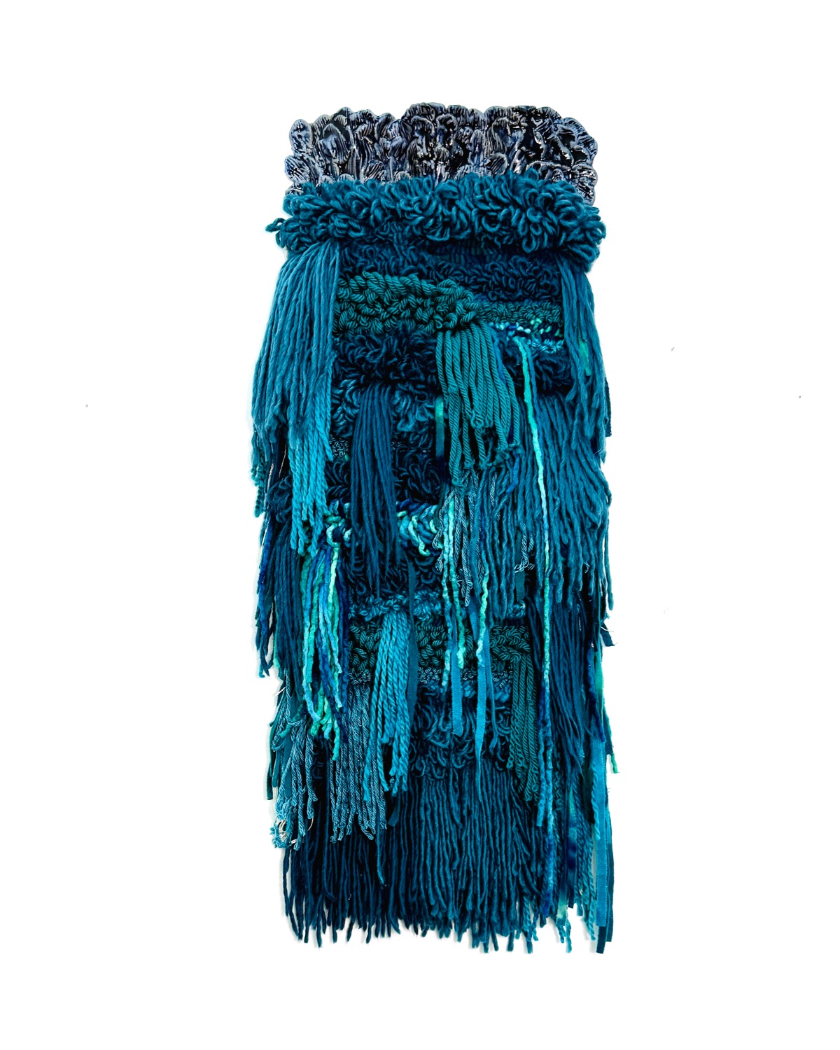 Long, textured blue and teal fringed skirt with ruffled waistband, hanging vertically against a white background.