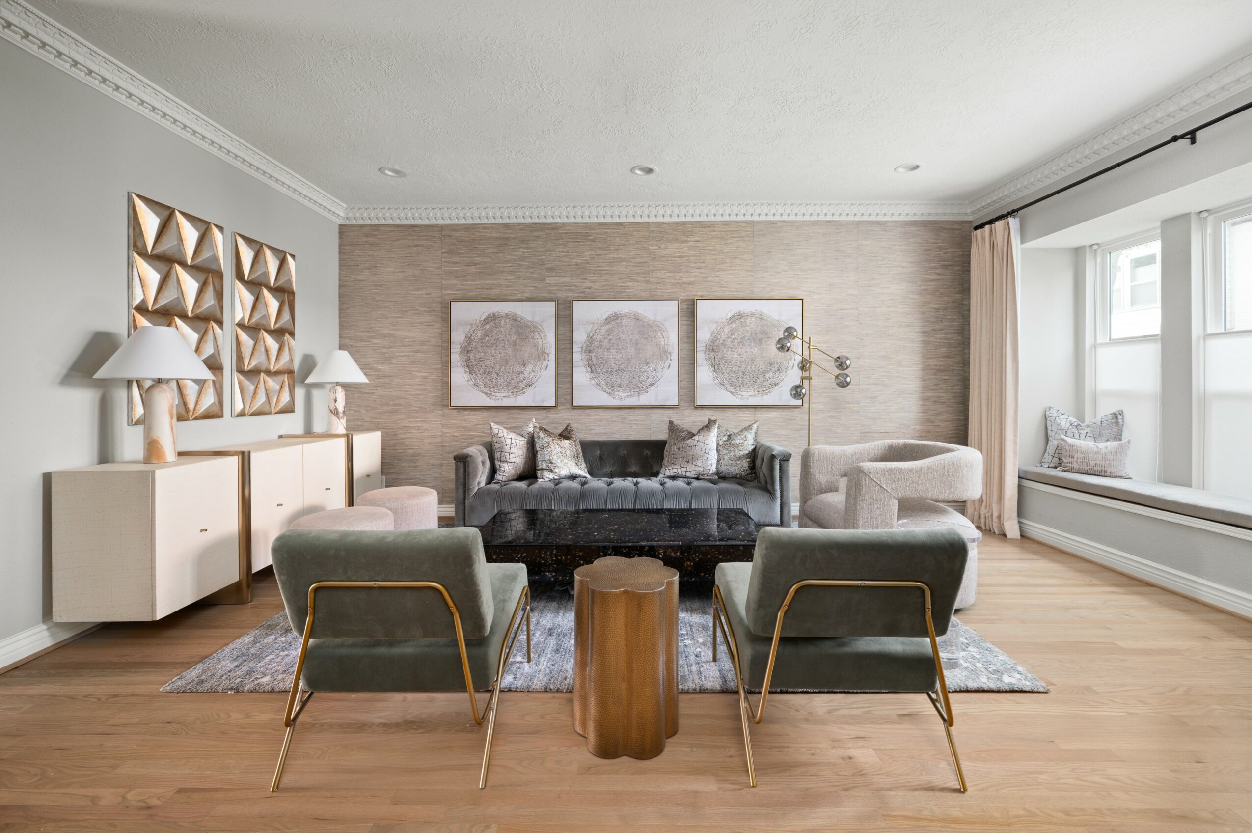 Living room with sofa, two armchairs, artwork, sideboard, and large window with curtains.