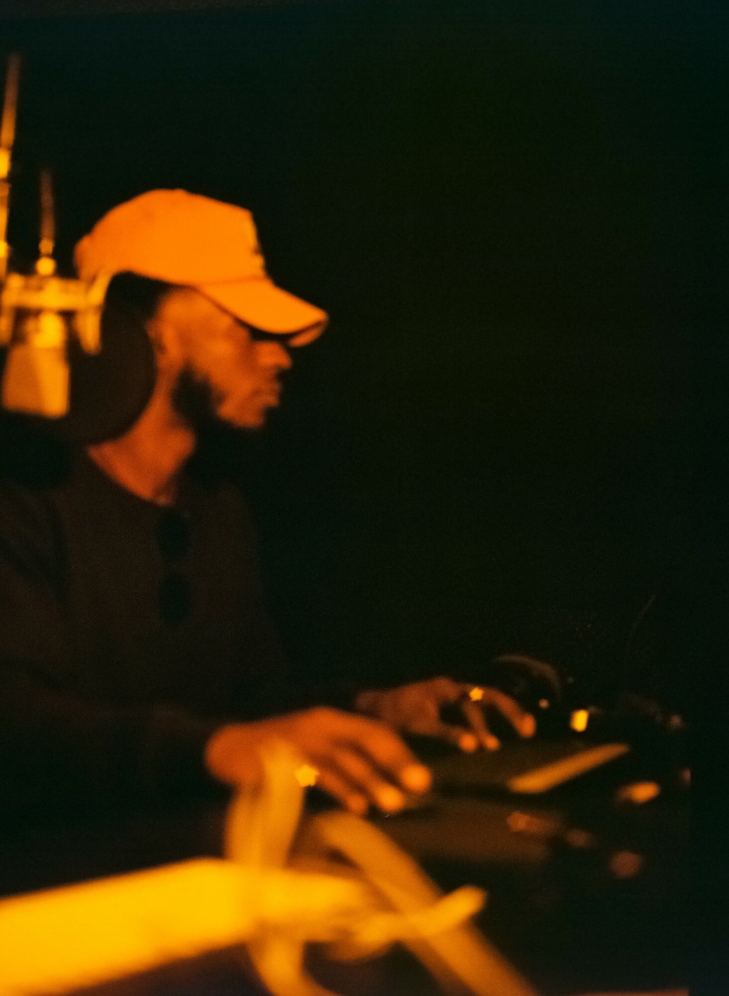 Person wearing a cap and glasses, operating equipment in a dark environment.